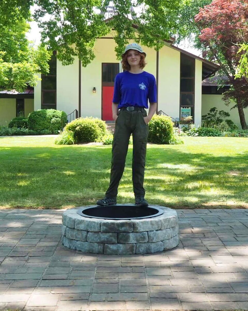 Jordan stands on top of the firepit and patio at the completion of her scouting project.